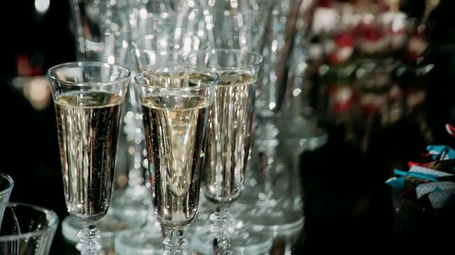 Champagne glasses stand in a row filled with alcohol and bubbles