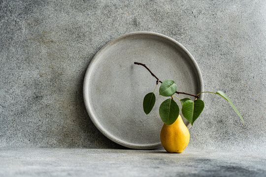 Minimalist pear and plate setting against neutral background