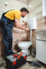 Plumber repairing toilet cistern in a bathroom
