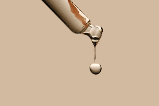 Serum in a pipette close-up on a beige background.