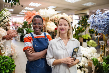 Two Smiling Florists Posing in Flower Shop with Digital Tablet