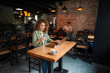 Freelancer is working at cafe using laptop and smartphone