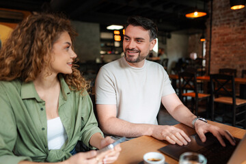 Young Couple Working on Laptop and Discussing in Cafe