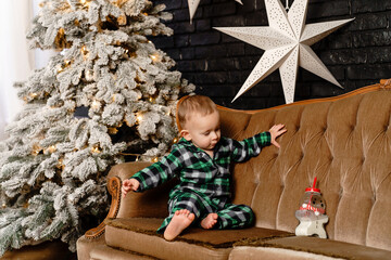 Little boy in green pajamas getting ready for Christmas, preparing milk for Santa