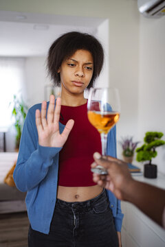 Young woman refusing a glass of wine offered by someone