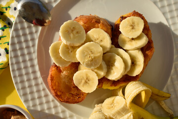 French toasts with banana slıces and open banana on whıte plate top vıew