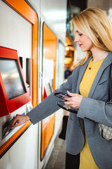 Woman buying public transport ticket at station machine