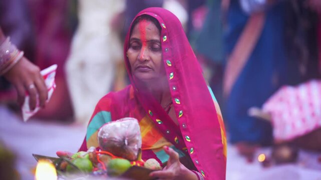 Close-up of woman offering coconut and fruits in soop during Chhath Puja sunrise ritual, representing faith and devotion.