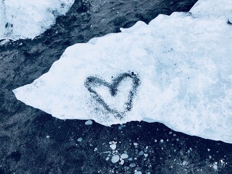 Heart shape drawn in sand on an ice block