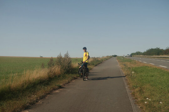 Cyclist pauses on rural path under blue sky