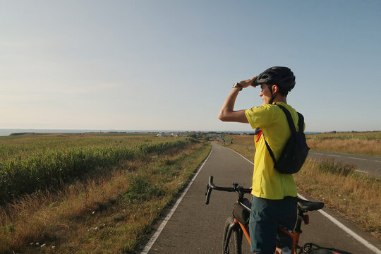 Cyclist pauses on rural path in Northern France under blue sky
