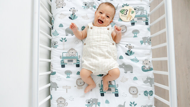 Smiling baby in a crib with safari-themed bedding