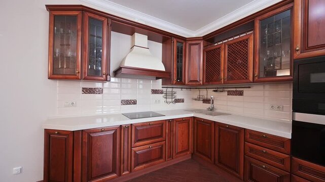 A classic kitchen features rich wood cabinets, a white countertop and backsplash. Glass accents are incorporated in upper cabinets