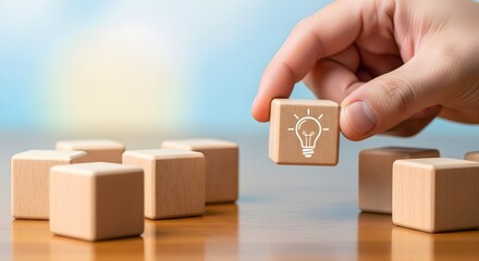 Hand arranging wooden blocks with light bulb icon for idea concept isolated on white background