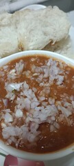 Close-up of spicy Indian pav bhaji served in a bowl, topped with finely chopped onions and accompanied by soft buttered pav bread, a popular Mumbai street food dish.