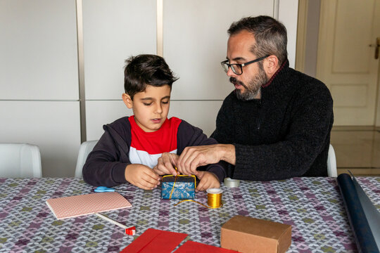 Father and son wrapping holiday gift together