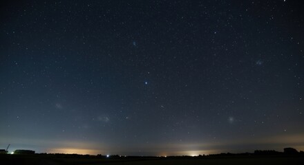 Vast star-filled night sky above a distant horizon with faint lights