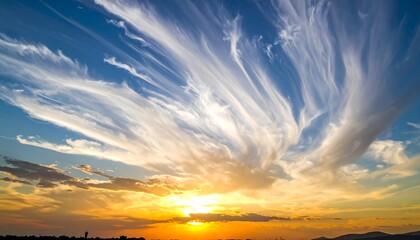 Golden sunset with striking white, wispy clouds streaking across a bright blue sky