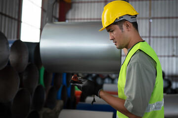 Worker inspecting metal sheets in industrial warehouse safety gear dressed factory environment close-up view manufacturing process