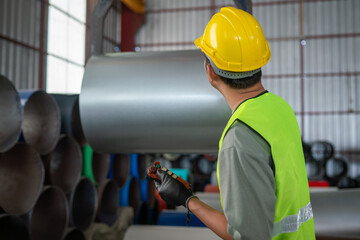 Worker inspecting steel pipes industrial warehouse action shot manufacturing environment side view safety procedures