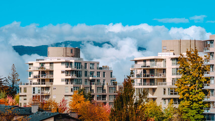 Mid-rise residential condos in a BC suburb during Fall, with mountain backdrop.