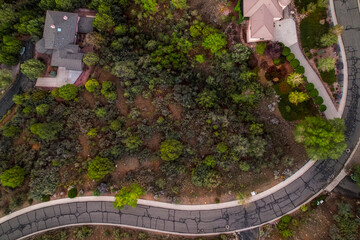 scenic winding rural route, aerial capture of tranquil hillside road with dwelling surroundings