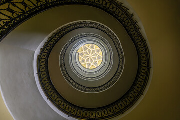 Upward view of decorative spiral stairs with geometric ceiling