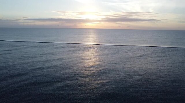 Drone captures sunset over ocean with visible protective barrier in water designed to keep predators away from shore safety and beauty coexist in peaceful evening view