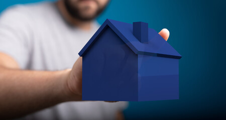 A man's hand holding a miniature blue house model. A visual representation of real estate, home ownership, and property investment. Symbolizing