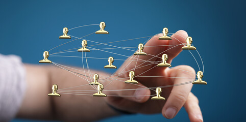 Close-up of a hand touching a network of golden human figures linked together, representing...