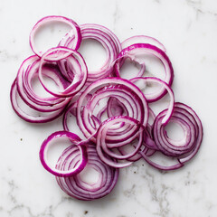 Thin red onion rings spread across white marble background, displaying translucent layers, color, and detailed texture.