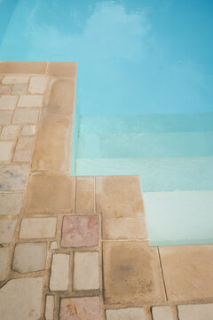 detail, border and steps of an italian swimming pool on the coast with blue water and terracotta tiles
