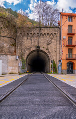 Fototapeta premium Ground-level view of the railway tracks towards the historic stone entrance of the railway tunnel in the town of Ripoll, Catalonia.