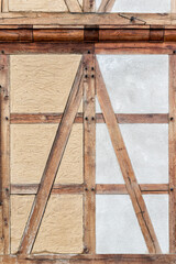 Close-up traditional half-timbered wall shows detailed wooden beams textured plaster panels. Warm tones aged wood contrast beige gray surfaces, reflecting historic craftsmanship rustic architecture
