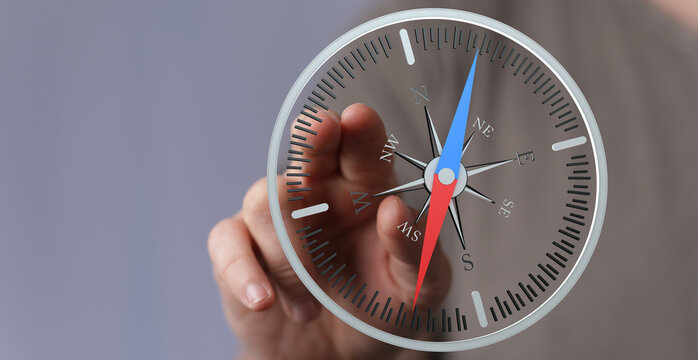 A close-up shot of a hand holding a compass, representing business guidance, direction, and strategy. Focus on navigation, orientation, and deci