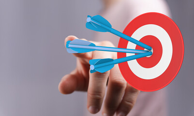 Concept of business goal. Person pointing at a target with arrows in the center, representing...