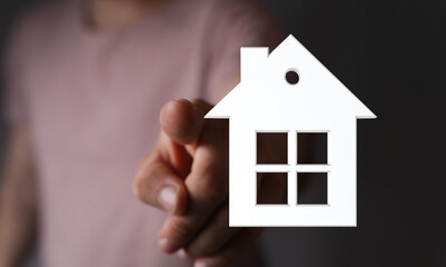Conceptual image of a hand pointing to a house icon. Symbolizes home, real estate, ownership, and dream home. Ideal for property, mortgage, and