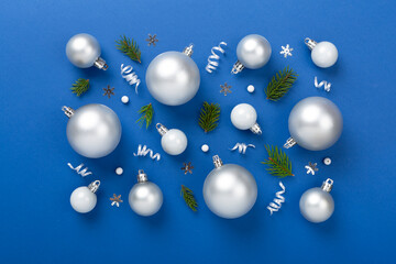 Grey Christmas balls with decor on color background, top view