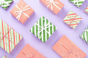 Many striped Christmas gift boxes on color background, top view