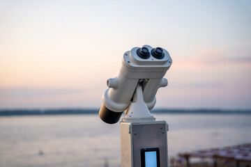 Coin operated binoculars facing sunset by the water