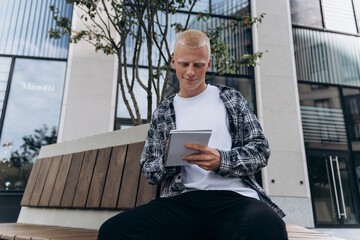 Young man writing in notebook outside modern building