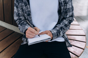 Young man writing in a notebook outdoors