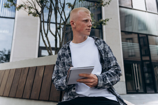Young man with albino appearance holding a notebook
