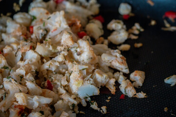 Close-up of sautéed cauliflower with herbs and red pepper pieces in a non-stick frying pan. Lightly browned, seasoned, and ready to serve as a healthy side or main vegetable dish.