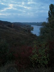 Steppe ravine and shrubs overlooking quiet reservoir at dusk
