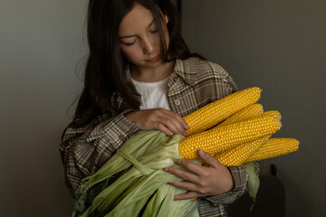 Preteen girl holding fresh corn in the kitchen
