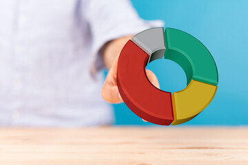 A hand holding a vibrant 3D pie chart, perfect for illustrating business data, market analysis, financial growth, and statistical reports.