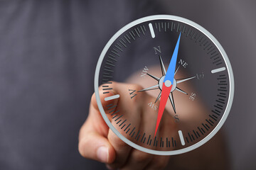 Hand holding a compass for direction. Navigation concept with the north and south indicators for...