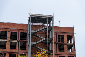 Construction progress of a modern building with steel staircase and brick walls