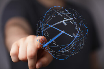 A person's finger pointing toward a digital sphere with time elements. Conceptual image about time, progress, and futuristic technology.